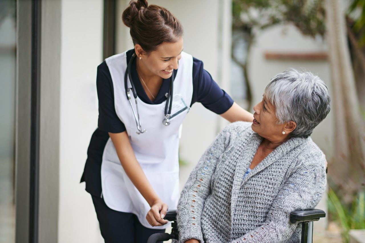 A nurse measuring the blood pressure of an elderly woman in a bright and comfortable bedroom.